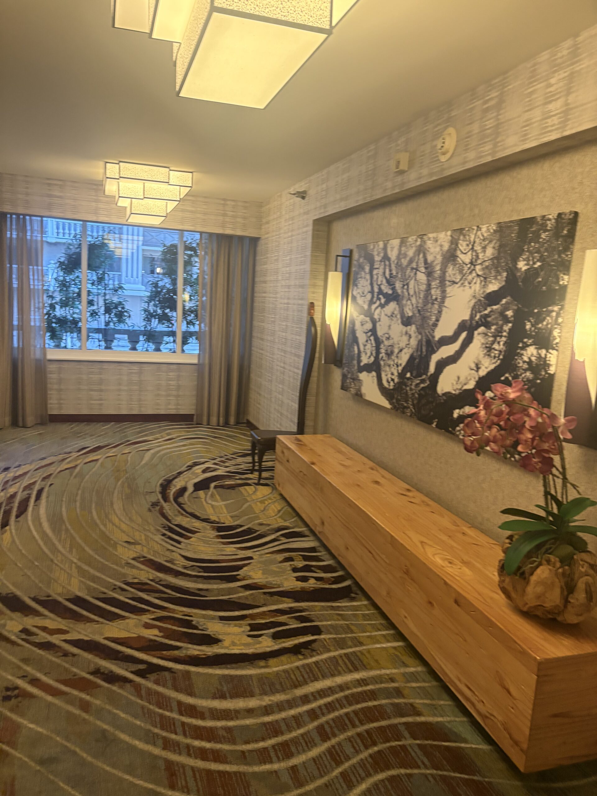 Hotel lobby area with wave-patterned carpet, wood bench, and black-and-white tree artwork at Nobu Hotel Las Vegas