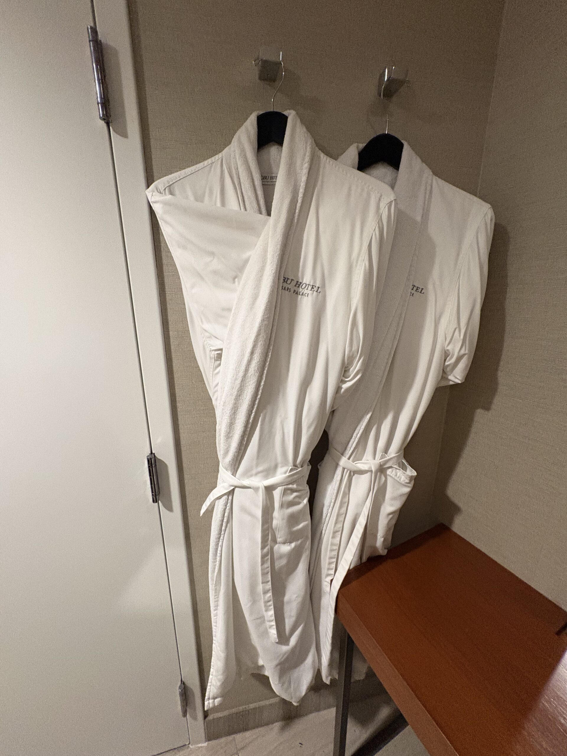 Two white Nobu Hotel Caesars Palace robes hanging on hooks in the closet