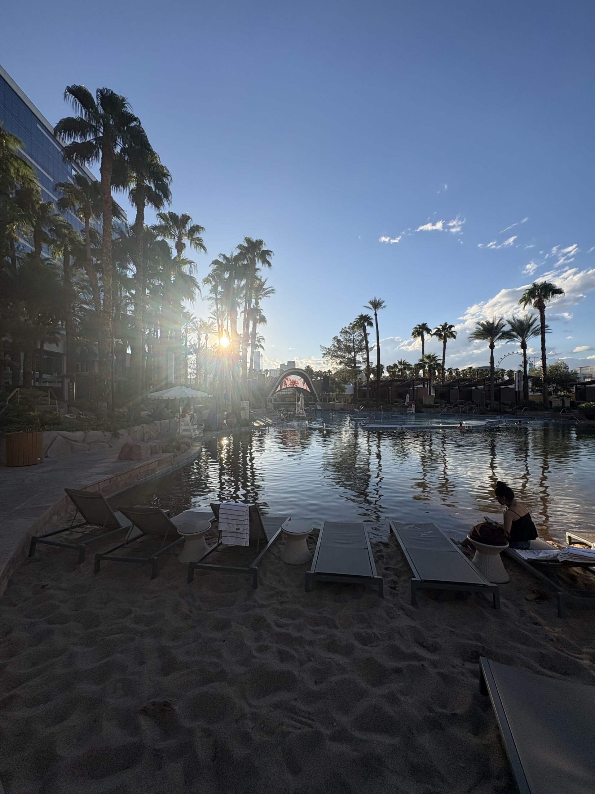Lounge chairs on the sand beach at the Virgin Hotels Las Vegas pool at sunset