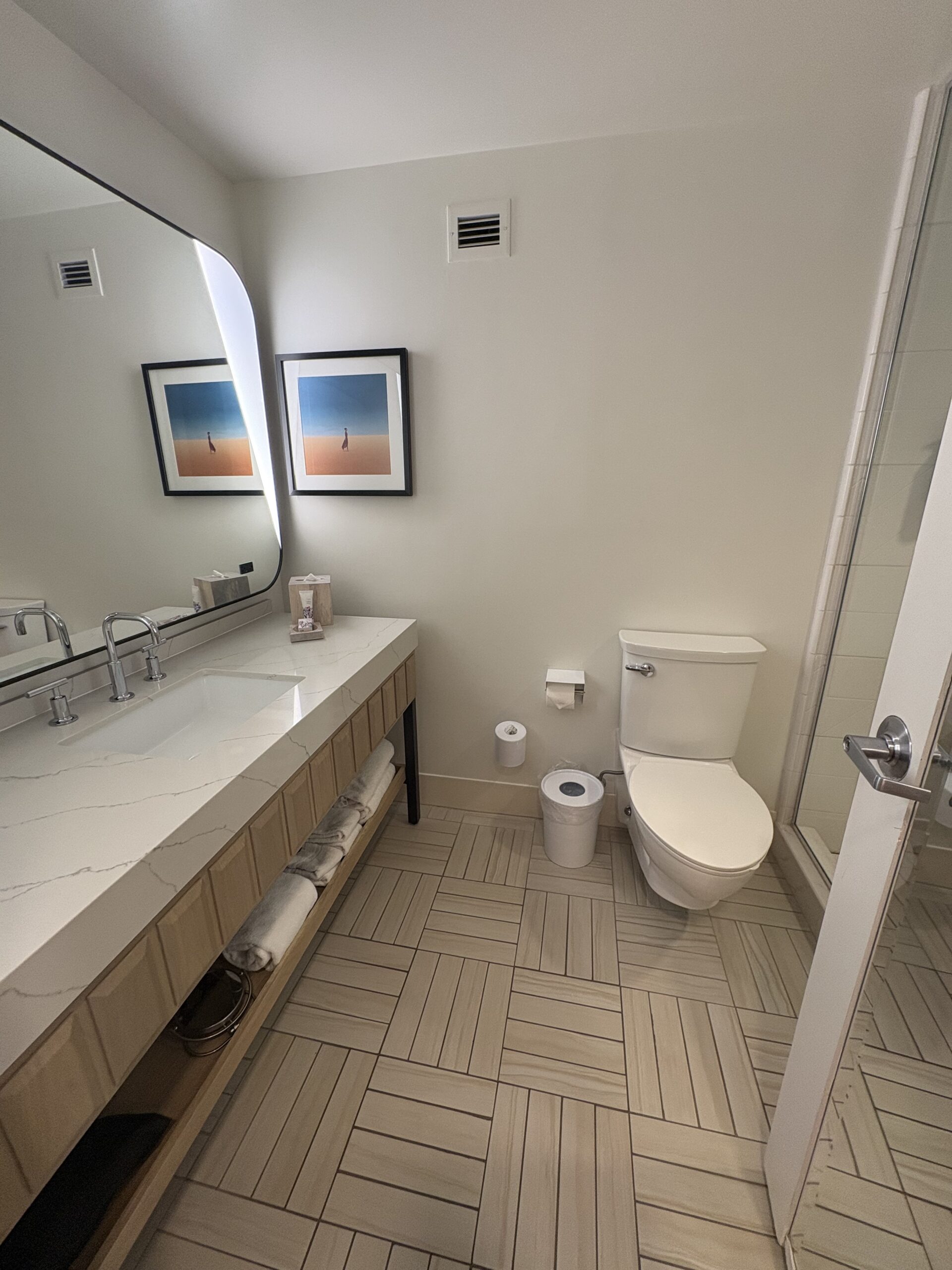 Long quartz bathroom vanity with rounded mirror and open towel shelf