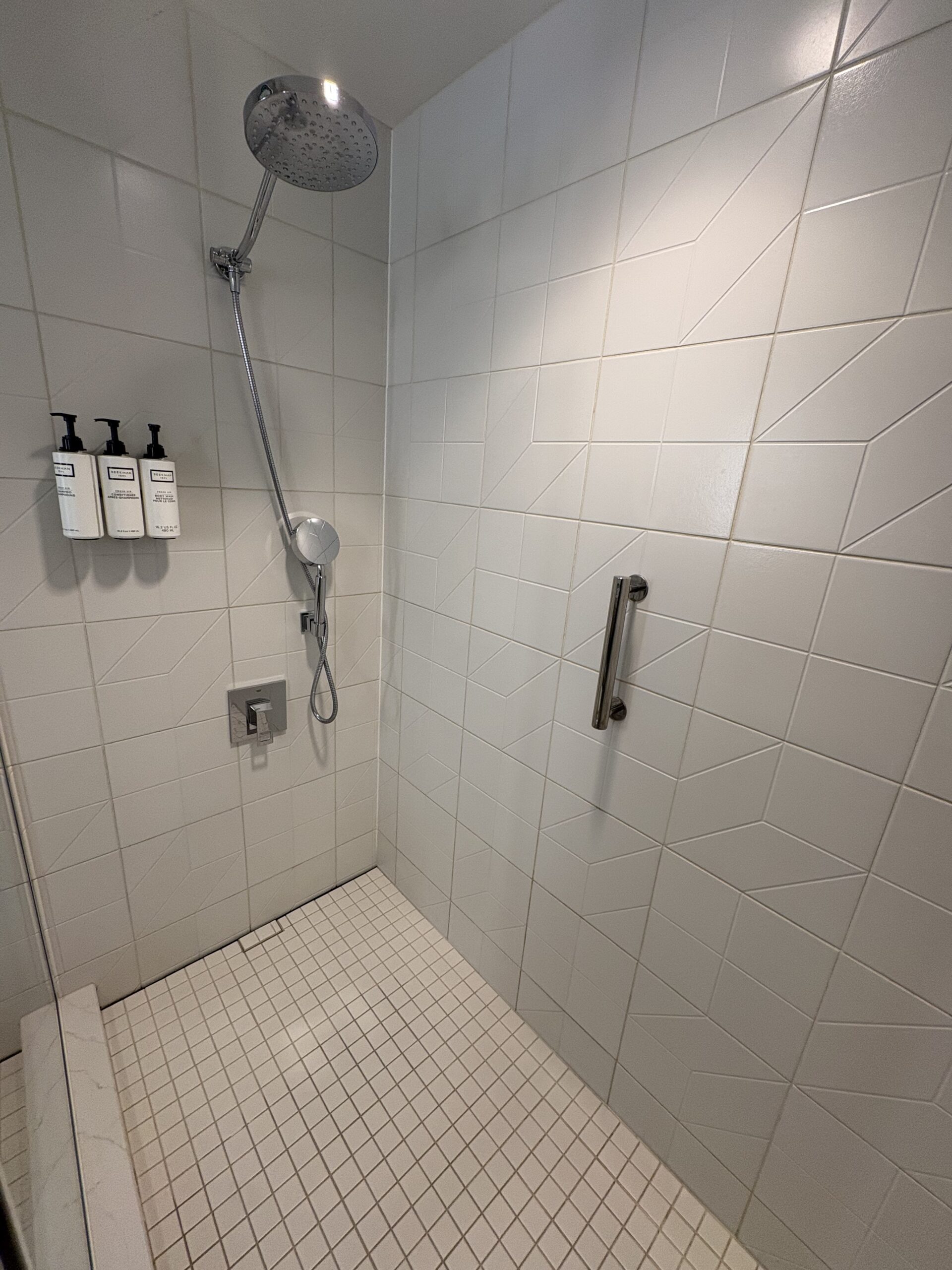 Walk-in shower with rain head, handheld wand, bench, and Beekman 1802 toiletries