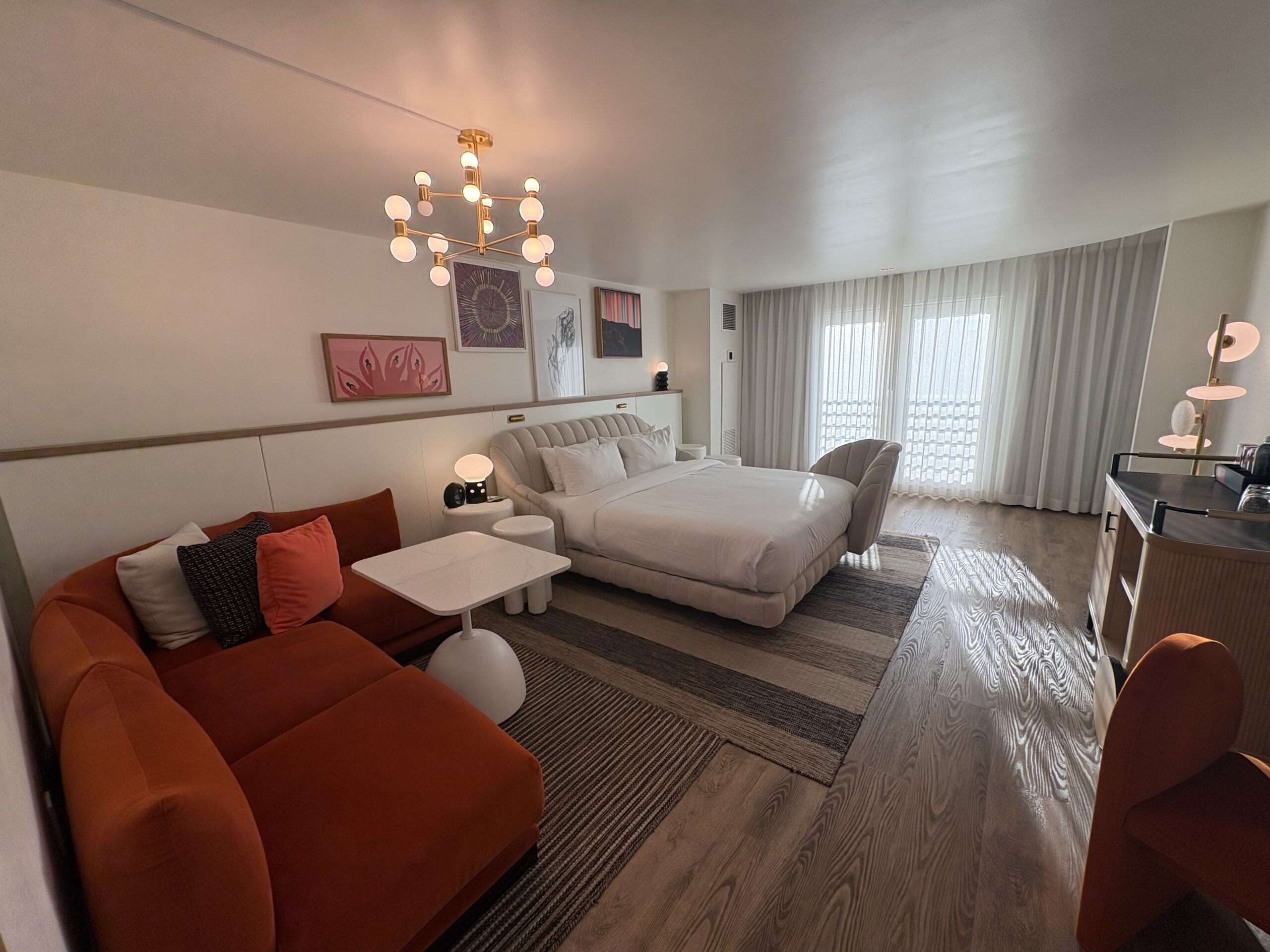 Strip View King Chamber at Virgin Hotels Las Vegas with rust velvet sectional, marble table, and king bed