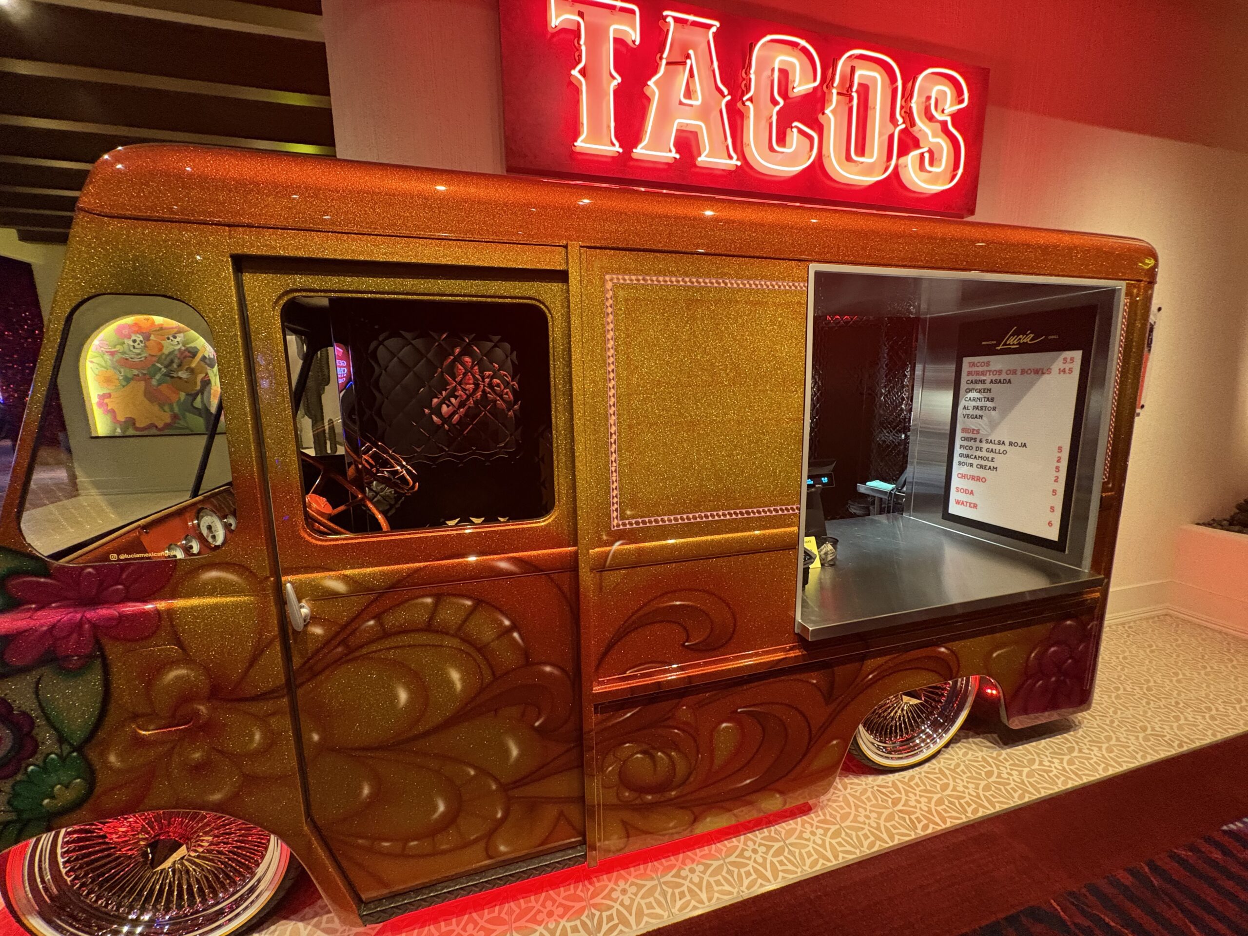 Glittery lowrider taco truck under a neon tacos sign at Virgin Hotels Las Vegas