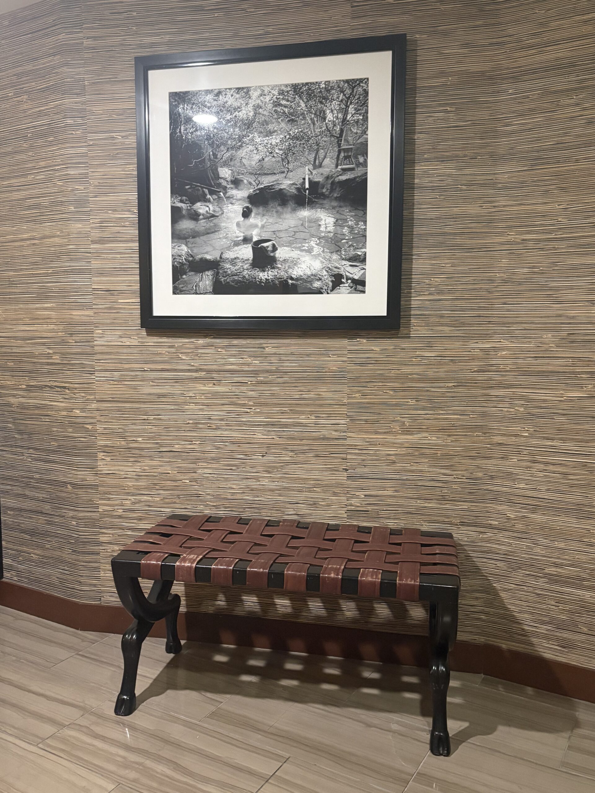 Framed black-and-white photograph of a traditional Japanese hot spring, displayed on the wall at Nobu Hotel
