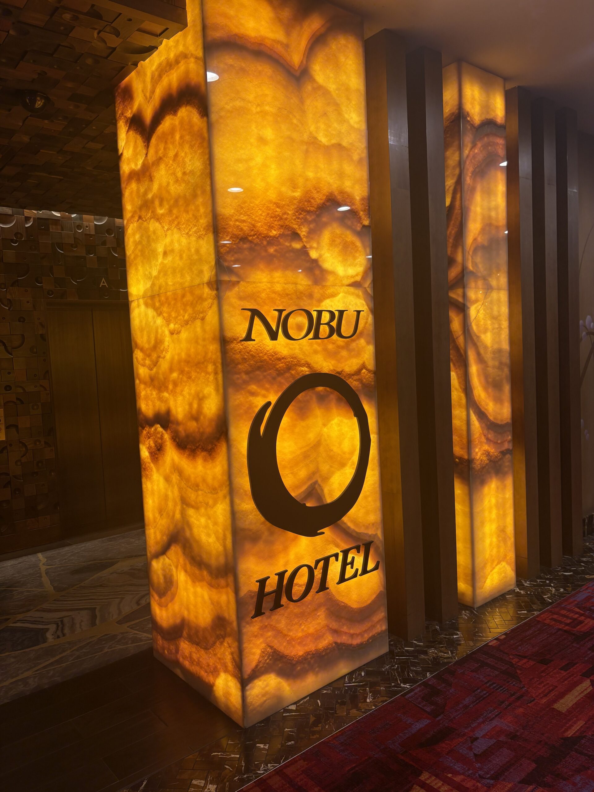 Illuminated amber onyx pillar with Nobu Hotel logo marking the entrance at Caesars Palace