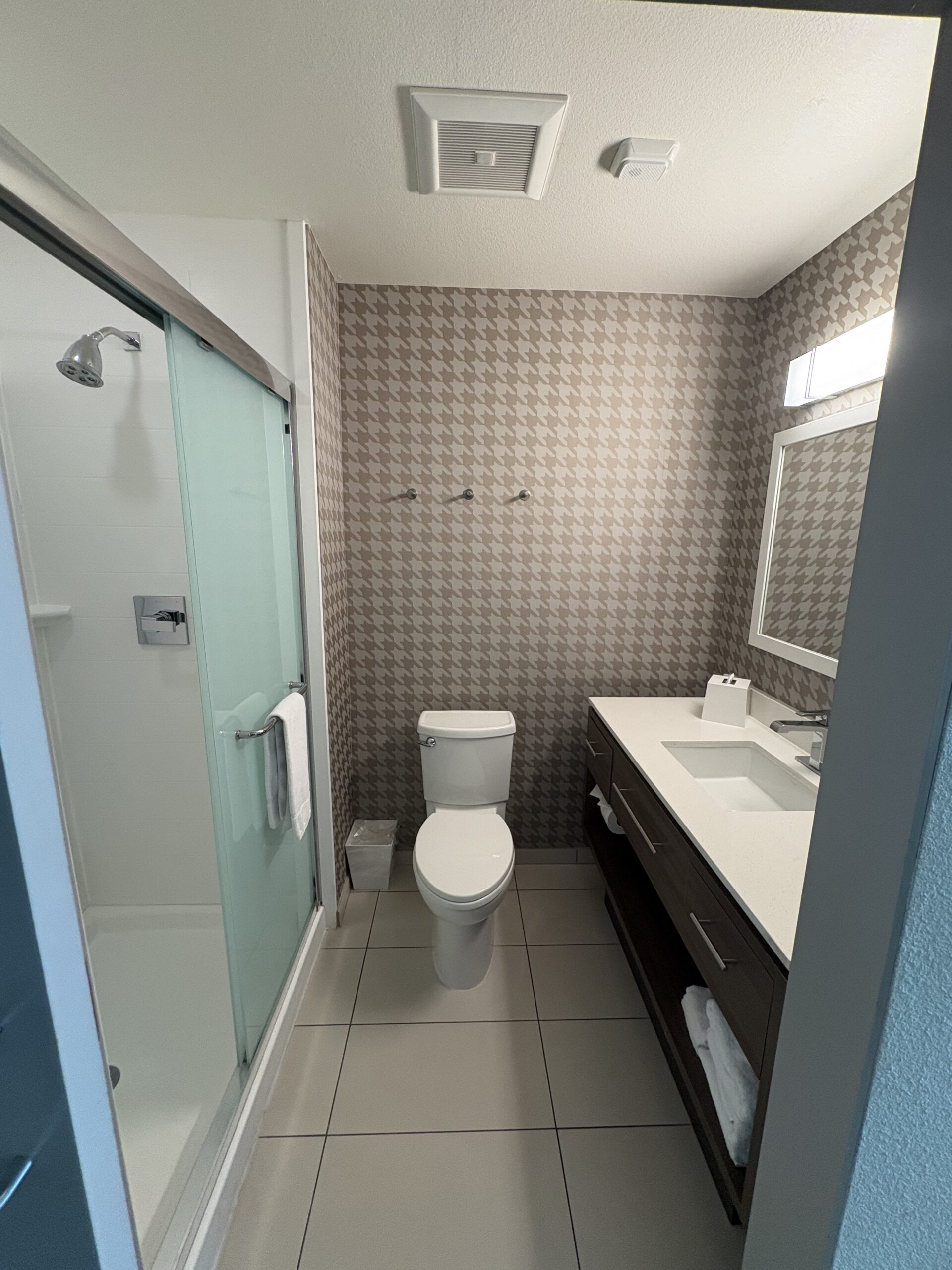 Bathroom with glass shower door and houndstooth wallpaper in Home2 Suites Stadium District