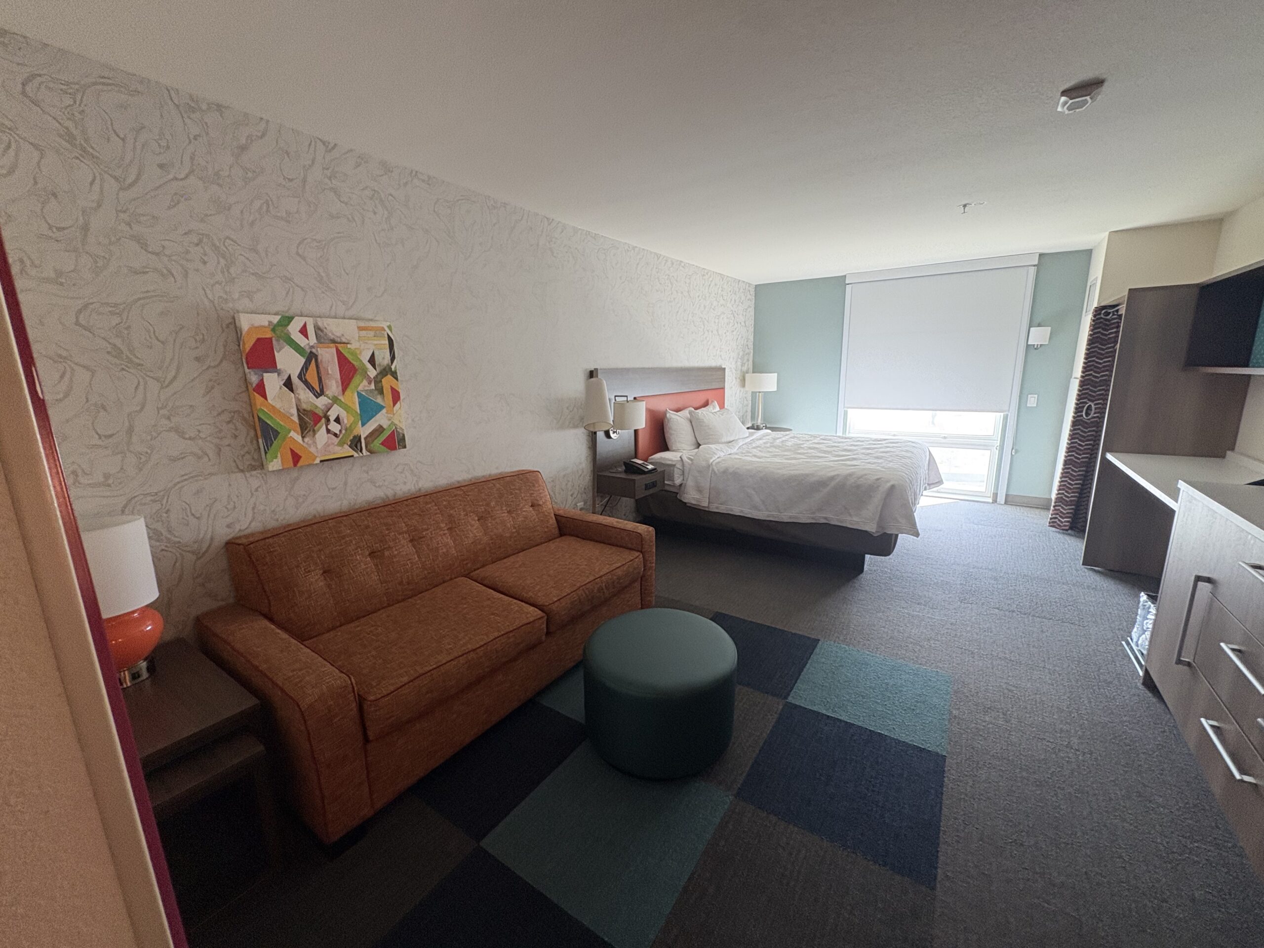 King bed and orange pullout couch in a Home2 Suites Las Vegas Stadium District suite