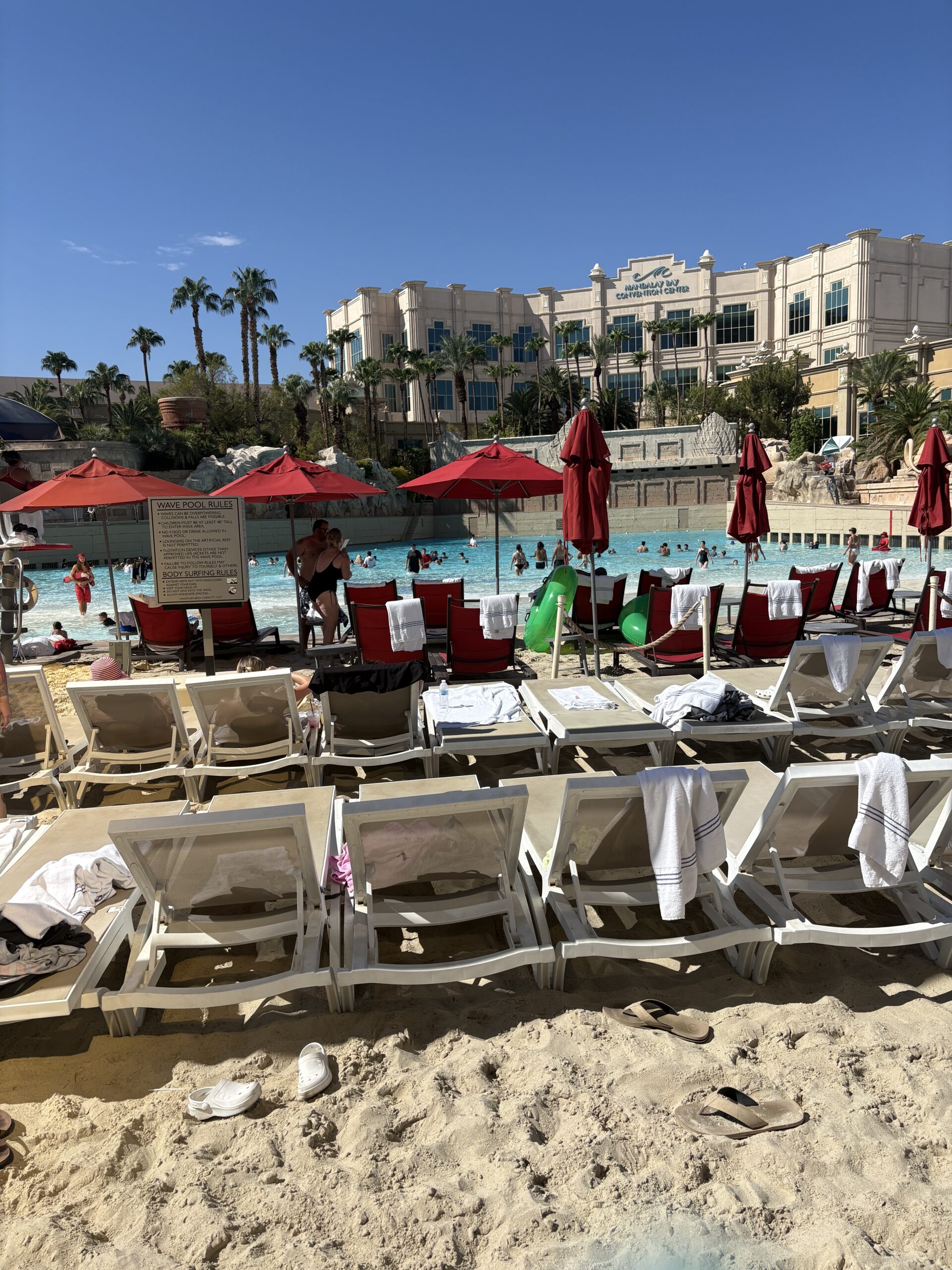 Sand beach with loungers and red umbrellas beside the wave pool at Mandalay Bay Las Vegas