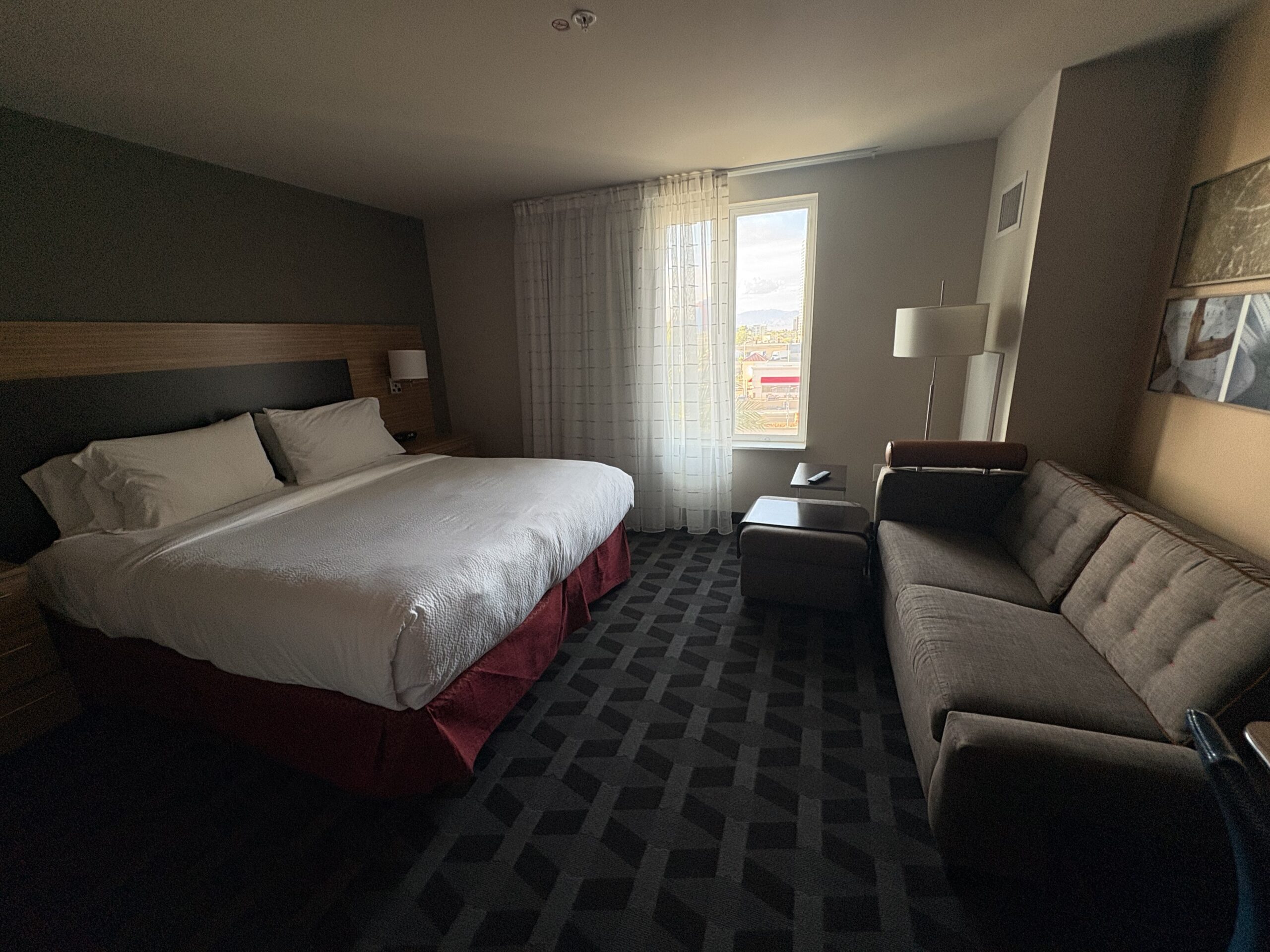 King bed with red bed skirt in a TownePlace Suites room near Allegiant Stadium
