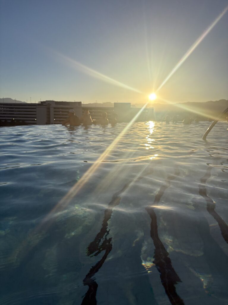 Infinity-edge pool at sunset with mountains in the distance