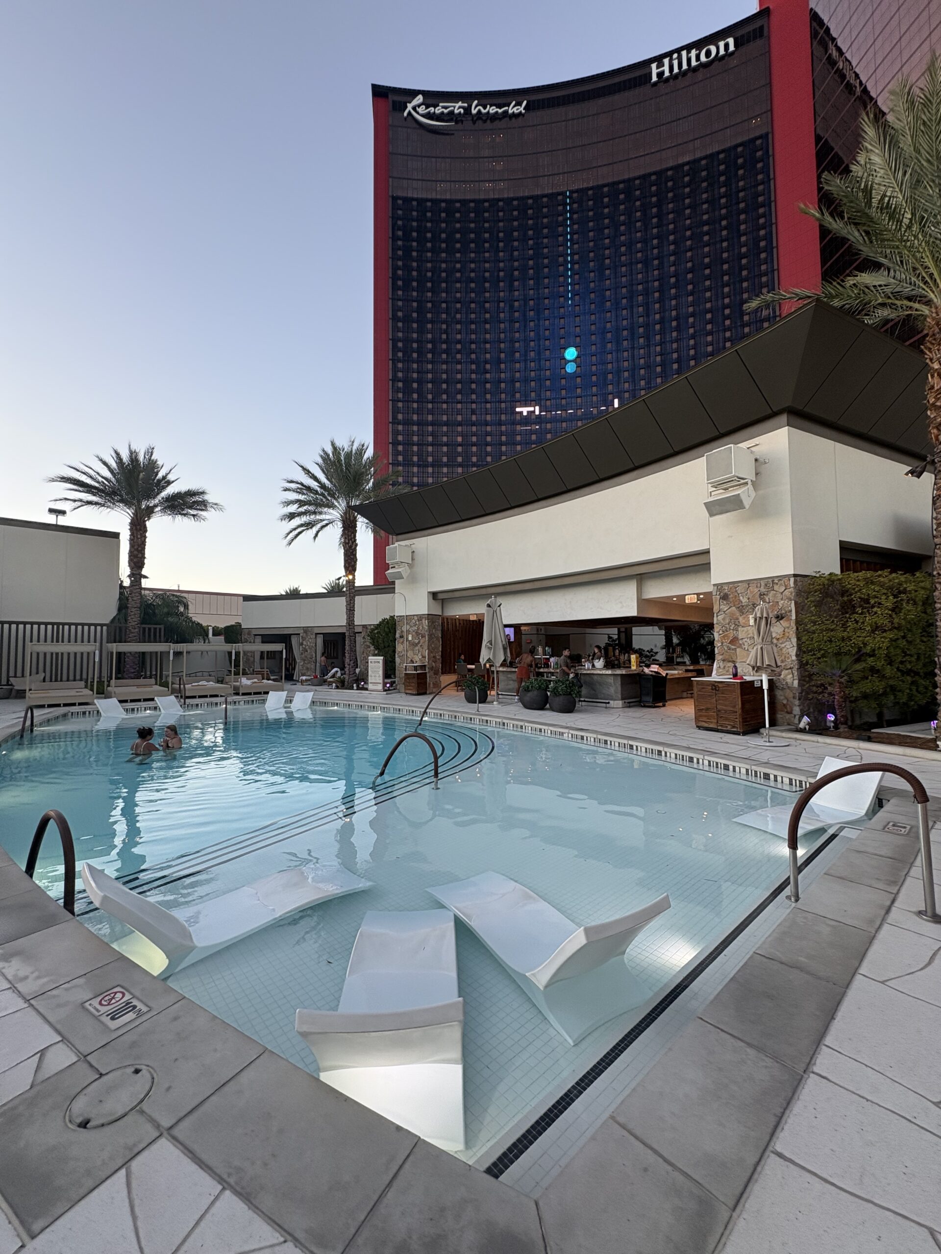 Pool with in-water loungers and a poolside bar, with the Las Vegas Hilton at Resorts World tower behind