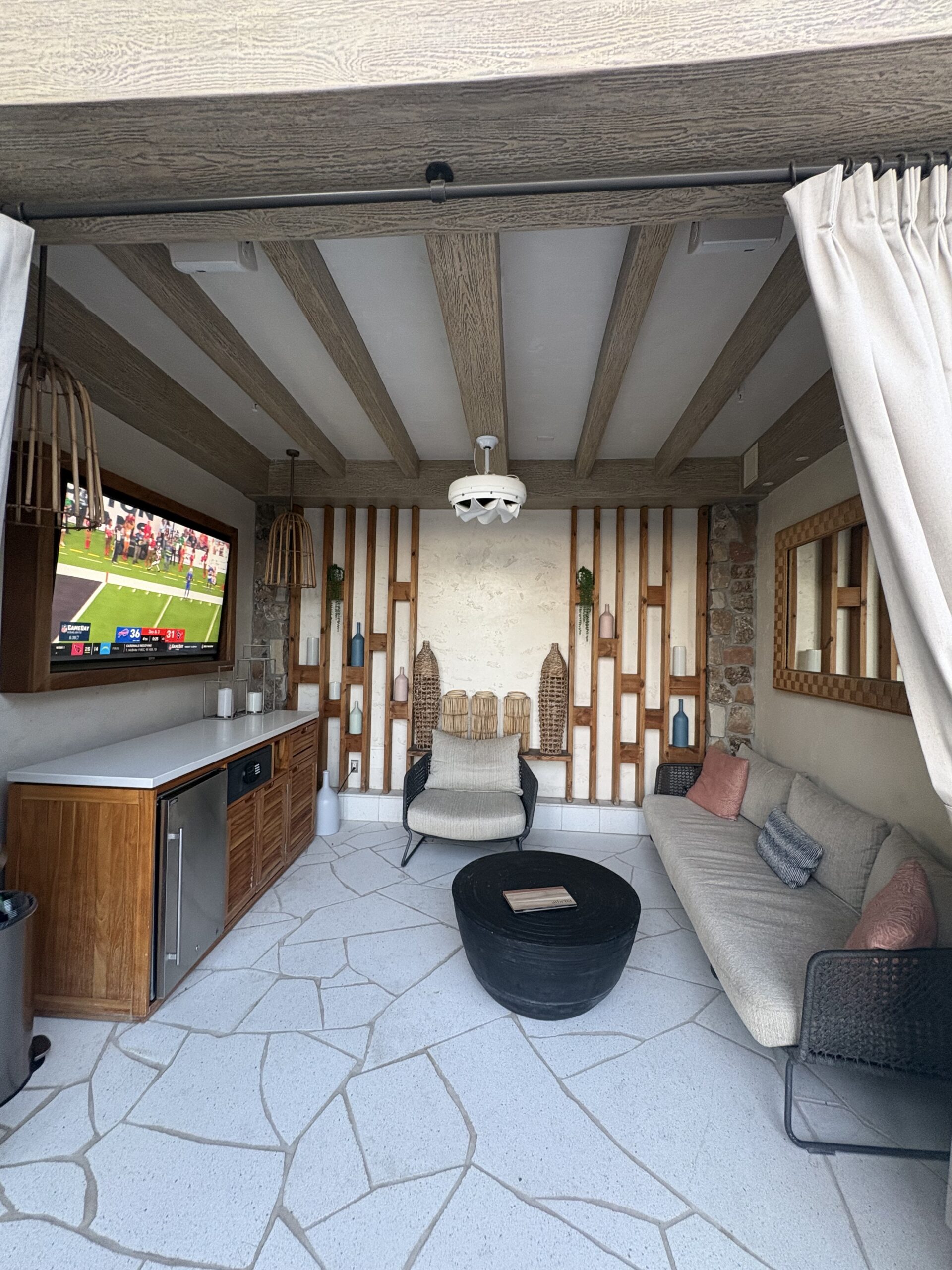 Covered poolside cabana with a TV, sectional sofa, and mini fridge at Resorts World