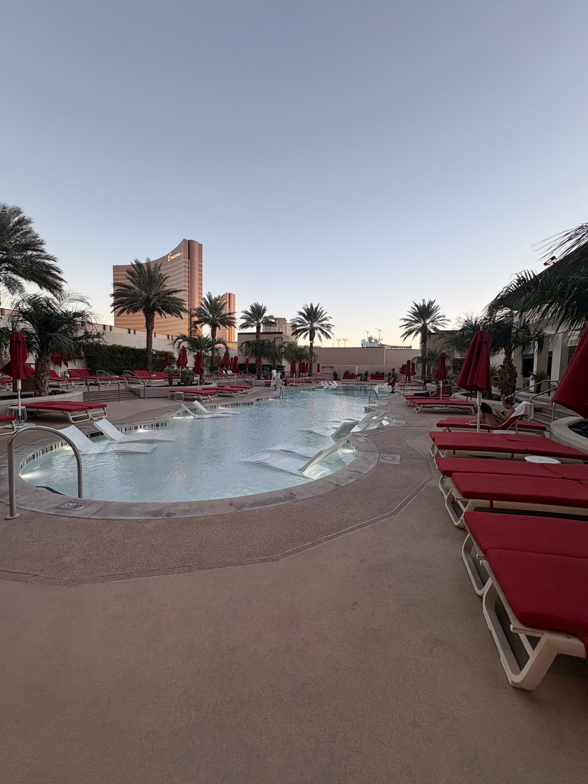 Resorts World pool with red loungers and the Encore tower in the background
