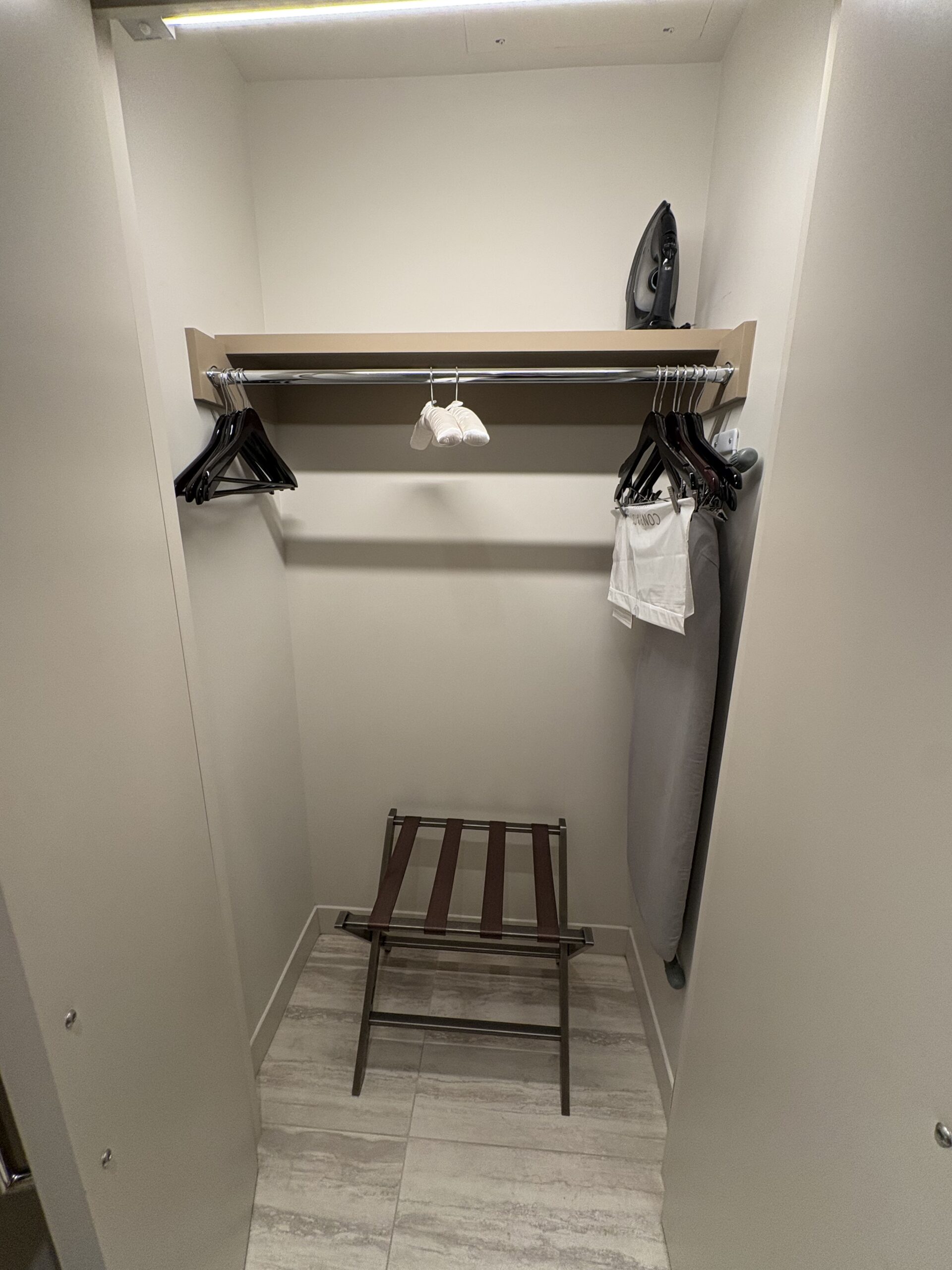 Walk-in closet with a luggage rack, iron, ironing board, and hangers in a Conrad Las Vegas room