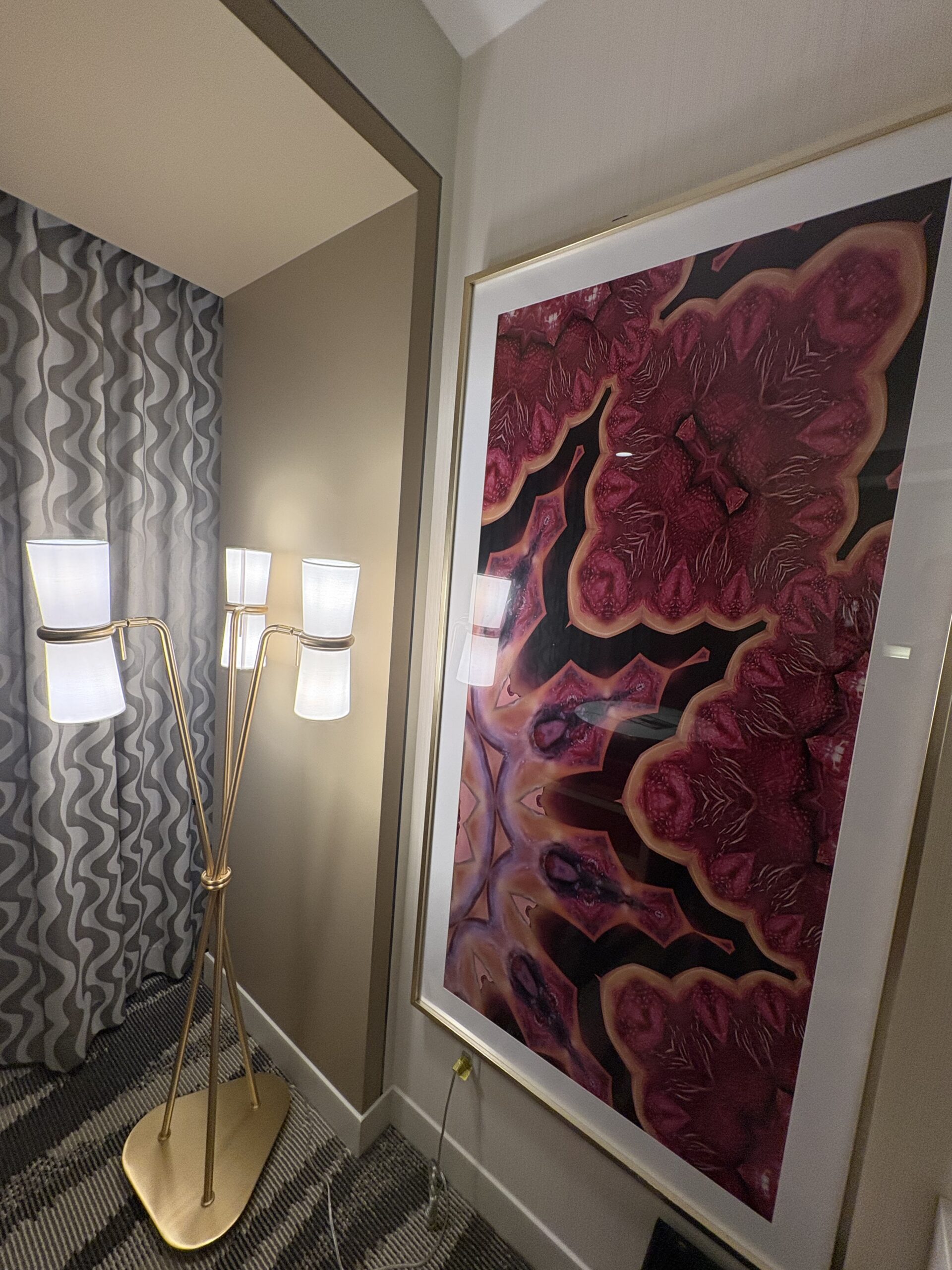 Large framed abstract print beside a gold floor lamp in a Conrad Las Vegas room