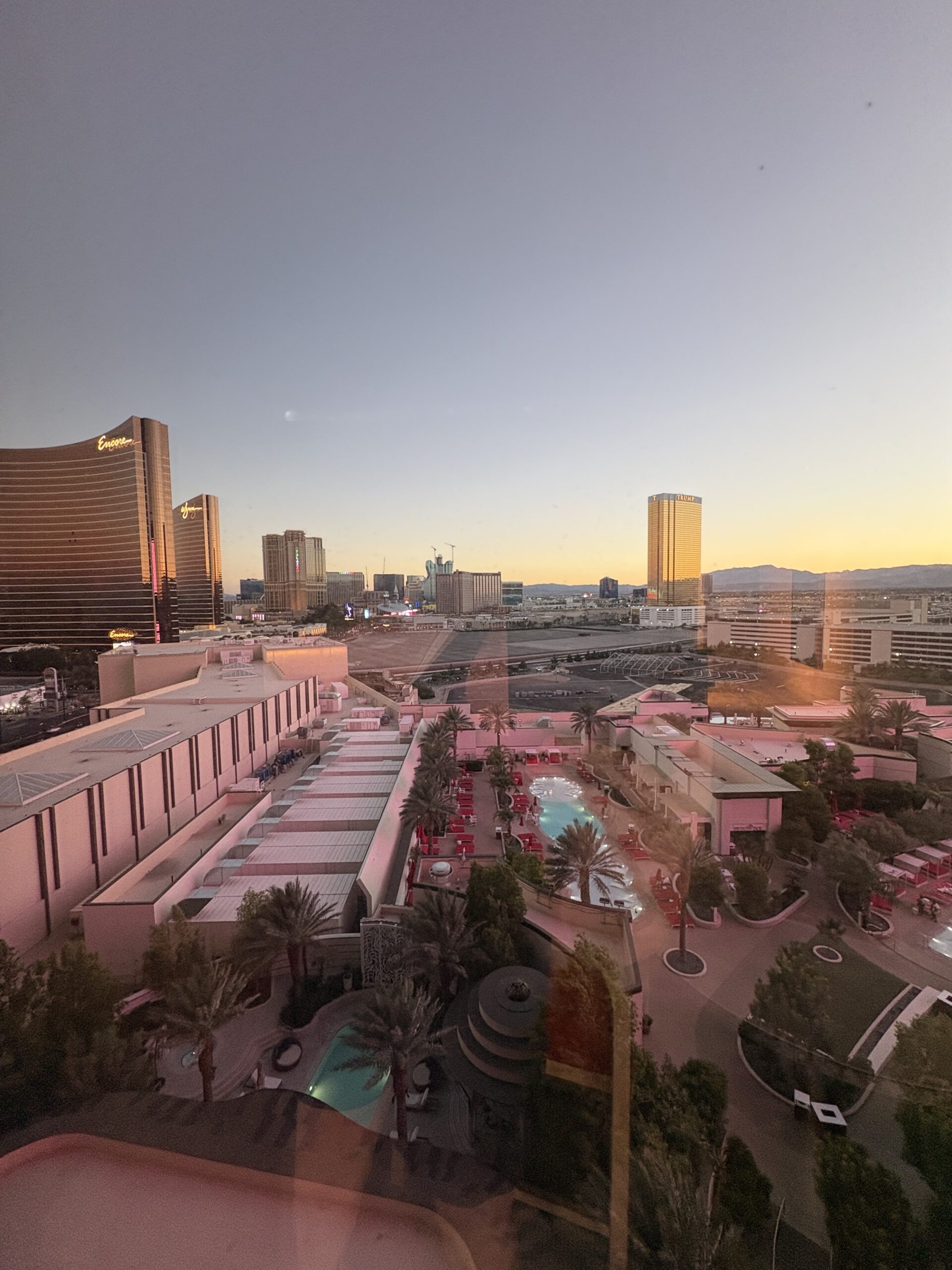 Sunset view from a Conrad Las Vegas room over the pool deck toward Encore, Wynn, and the Trump tower