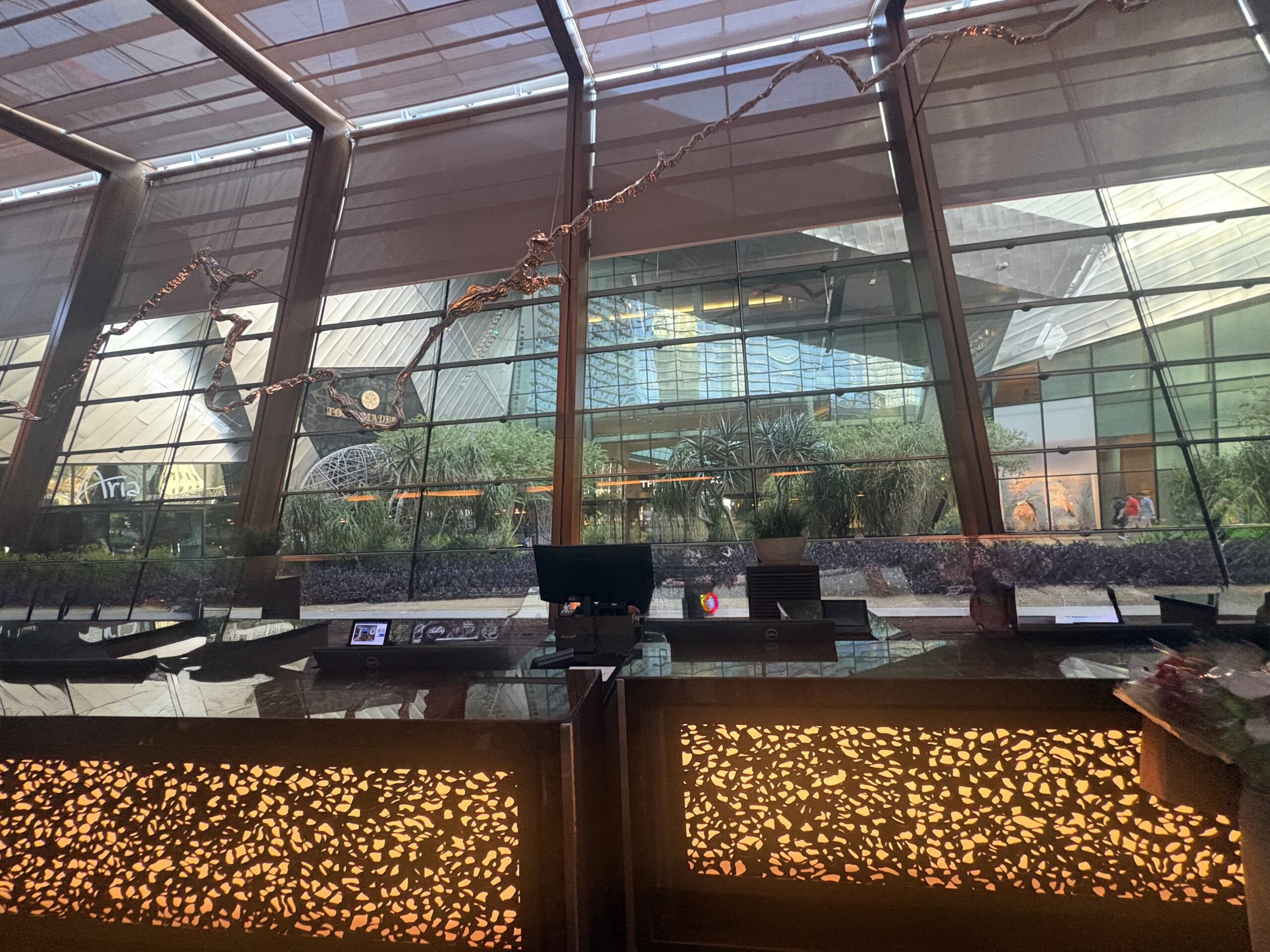 Backlit Aria front desk with a garden behind the glass windows
