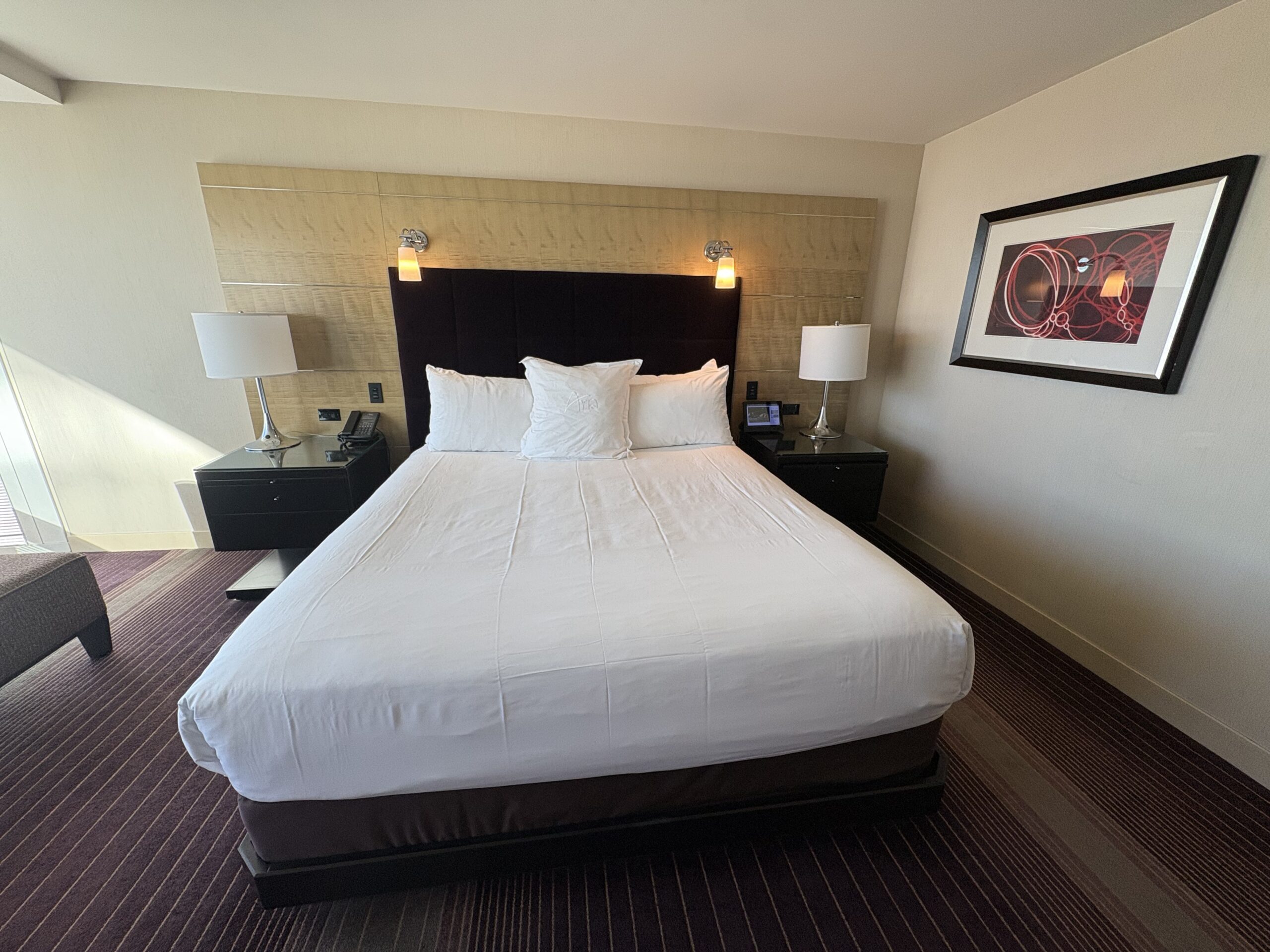 King bed with an Aria-embroidered pillow and reading sconces