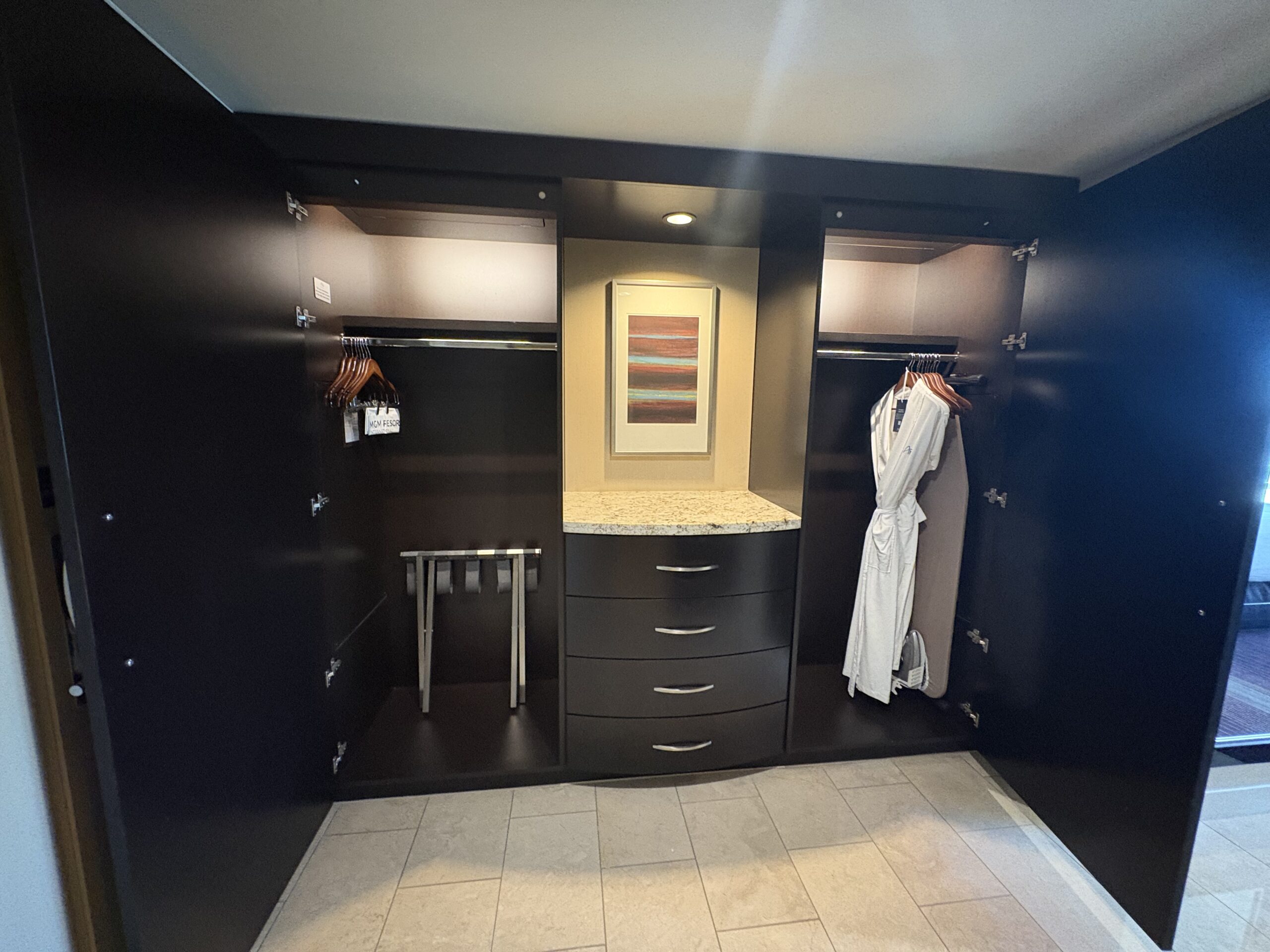 Built-in wardrobe with robes, hangers, dresser, and luggage rack