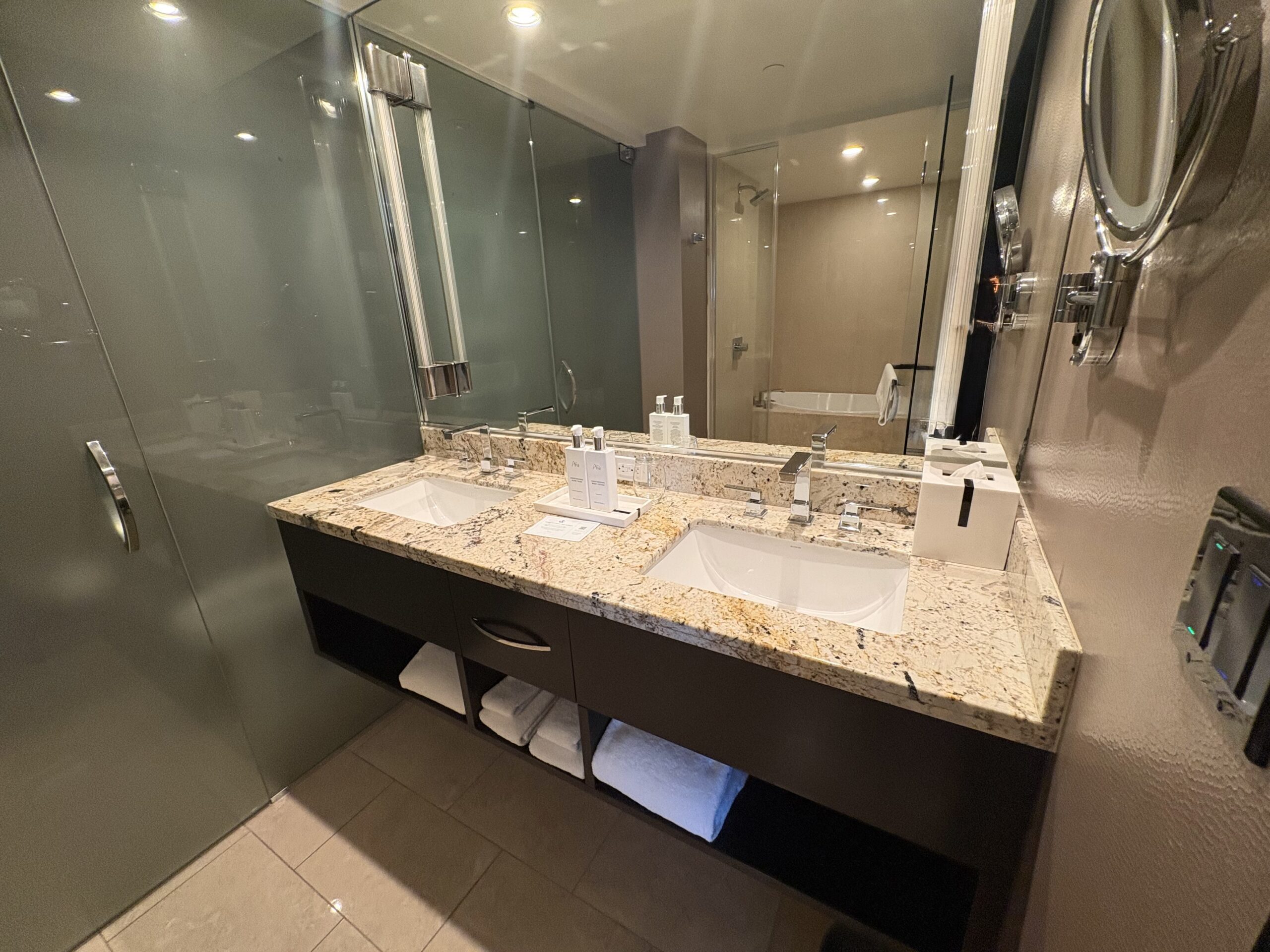 Double vanity on granite with towels and a lighted magnifying mirror