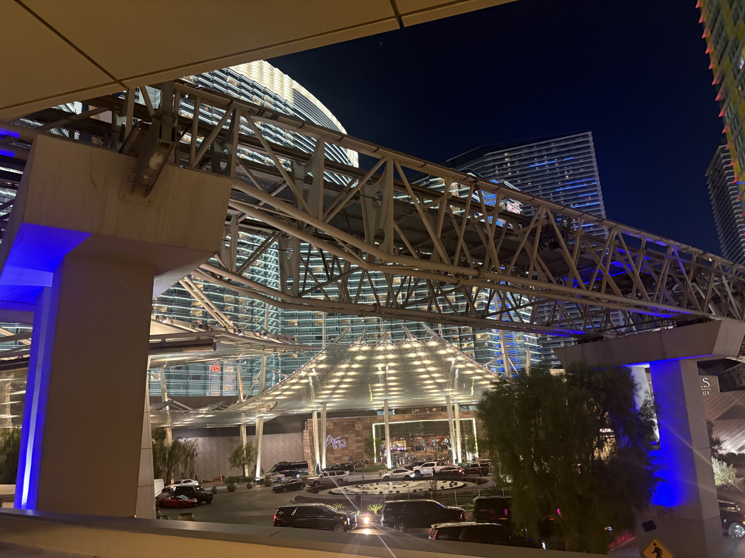 Aria Las Vegas main entrance at night with lit canopy, front circle, and tram track overhead