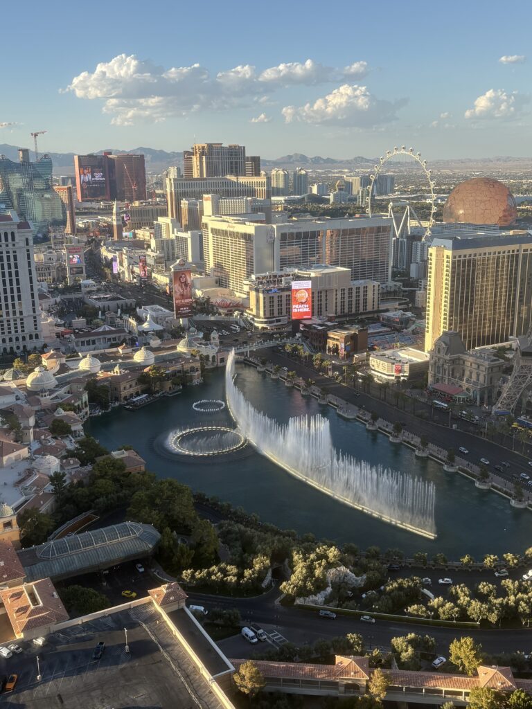 Bellagio fountains mid-show seen from a high-floor Cosmopolitan Las Vegas fountain-view room, with the Strip behind