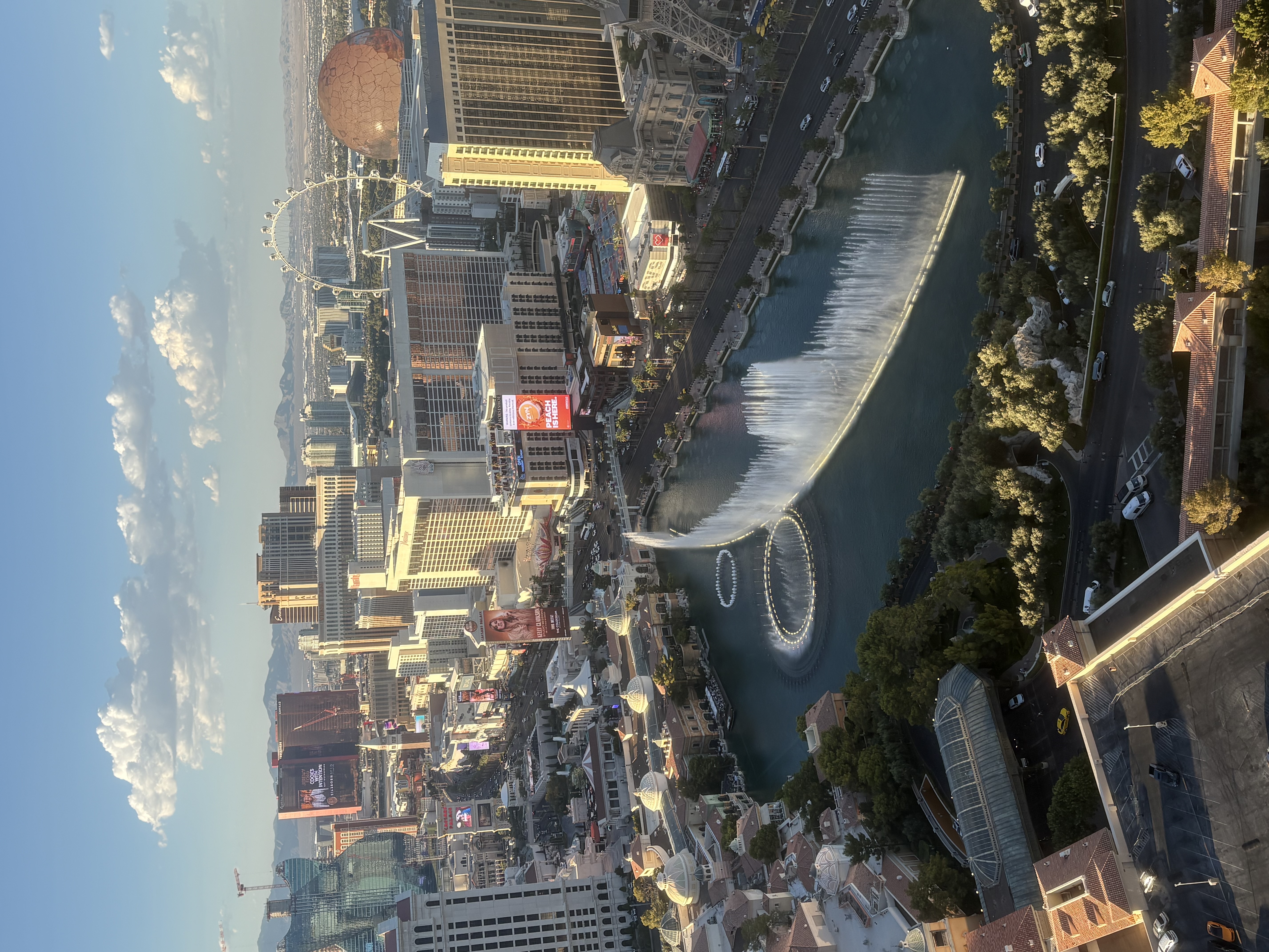 Bellagio fountains mid-show seen from a high-floor Cosmopolitan Las Vegas fountain-view room, with the Strip behind