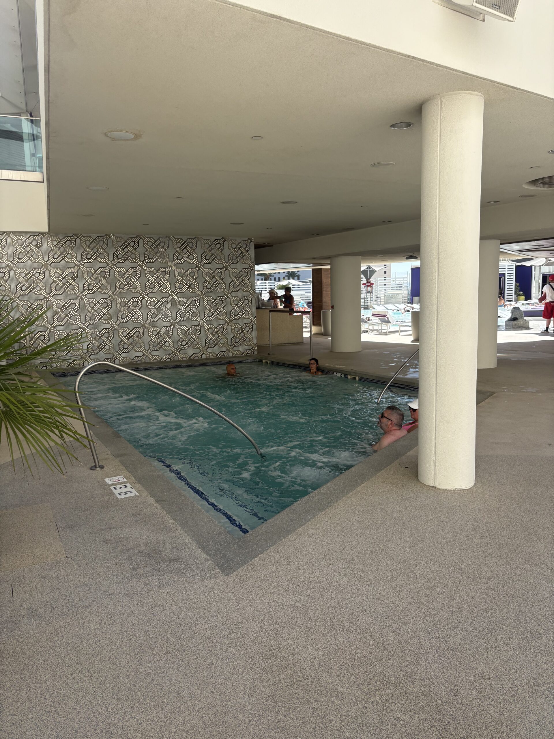 Covered jacuzzi at the Cosmopolitan Las Vegas Boulevard Pool, shaded under the building with the pool deck beyond